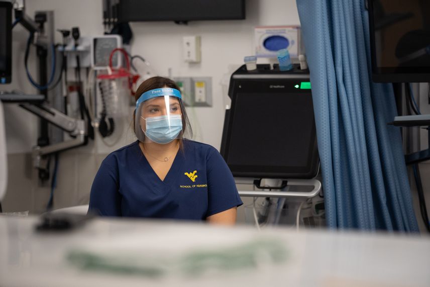 A WVU School of Nursing student wears a face mask and a face shield during a hands-on lecture in the Health Sciences patient simulation center.