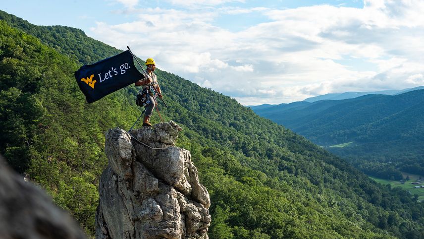 A student flies a Let's Go flag atop Seneca Rocks in West Virginia. 