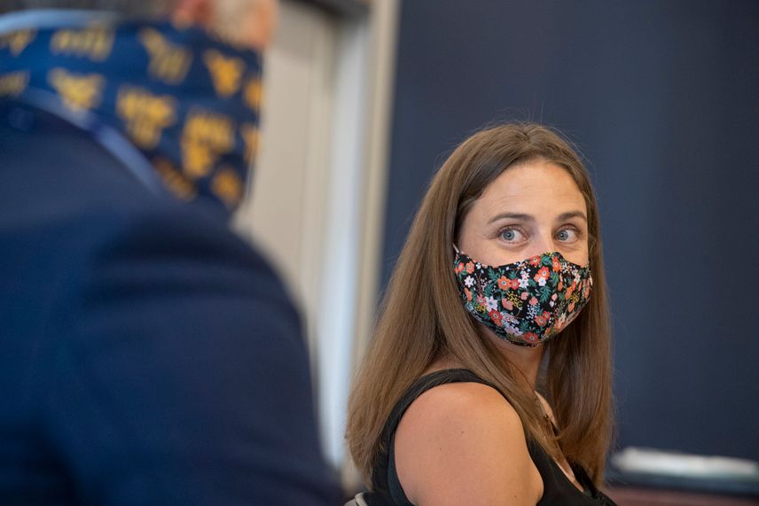 A WVU faculty member wearing a mask looks at her colleague, also wearing a mask.